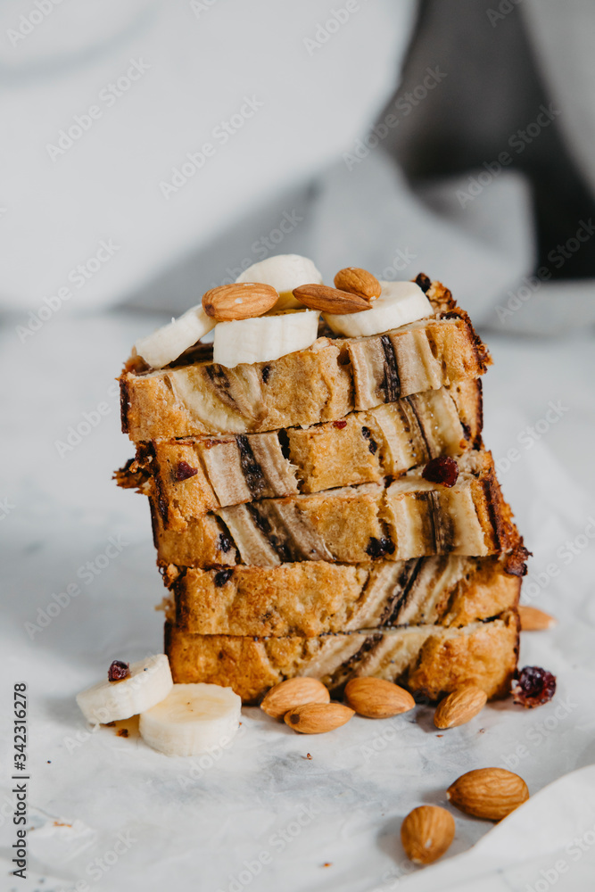Butter-free, sugar-free banana bread with oat flour, soft curd cheese and honey. Top view of sliced banana bread on gray marble background. Ideas and recipes for healthy diet breakfast