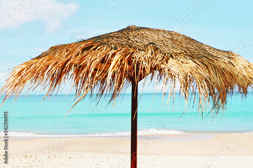 close up of a beautiful straw umbrella ,isolated on the beach at daytime on the empty beach, bright blue water and sky, paradise tropical beach,relaxing time,,amazing view,no people