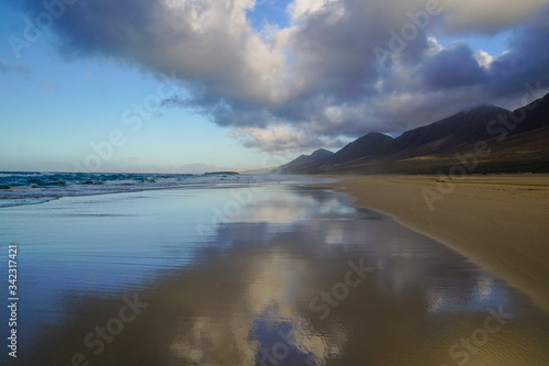 COFETE BEACH,FUERTEVENTURA - JANUARY 19, 2020: The mountains of Jandia National park are reflecting in the sea 