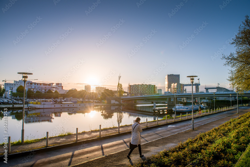 femme allant au travail au premier rayon du soleil le long des quais du canal de Nantes