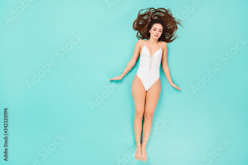 Top above high angle view full length photo of sleeping girl wearing white swimwear bikini laying on beach sunbathing want be tanned skin isolated over teal color background © deagreez