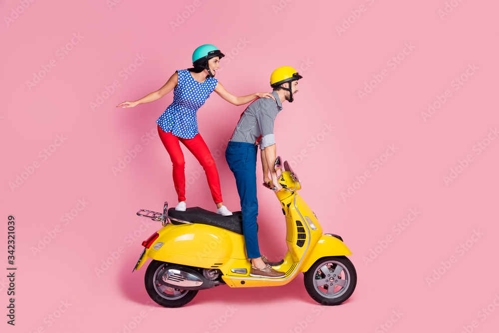 Full size profile side photo of careless cheerful wife husband extreme sport motorcyclist ride yellow chopper electric scooter stand look distance road isolated over pastel color background Full size profile side photo of careless cheerful wife husband extreme sport motorcyclist ride yellow chopper electric scooter stand look distance road isolated over pastel color background
