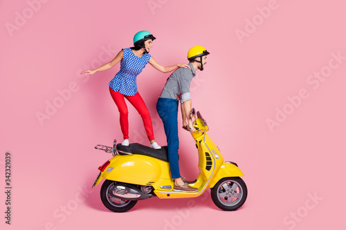 Full size profile side photo of careless cheerful wife husband extreme sport motorcyclist ride yellow chopper electric scooter stand look distance road isolated over pastel color background © deagreez