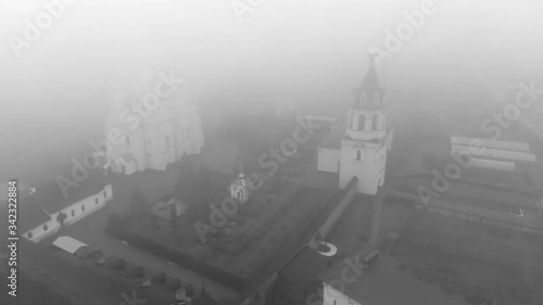 Morning flight in the fog over an Orthodox monastery. Black and white video. Beautiful view of Zimnensky Svyatogorsky monastery from above. View of the domes and the Assumption Cathedral. photo