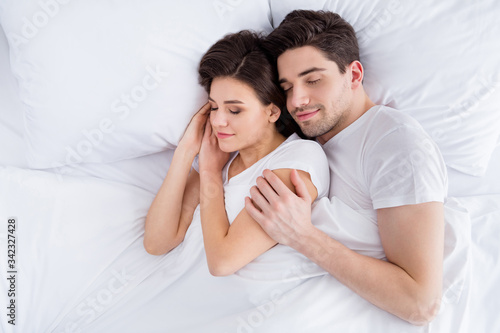 High angle above top view photo charming lady husband guy couple lying comfortable sheets bed white blanket hugging joyful hold touch arms eyes closed wear pajama room indoors