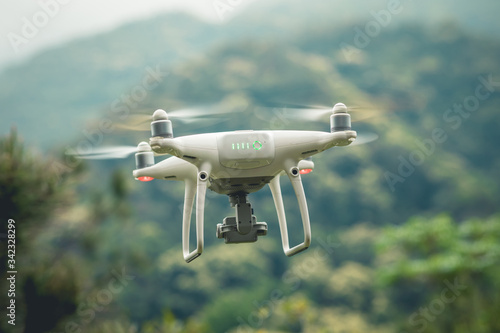 White drone with camera flying in tropical forest