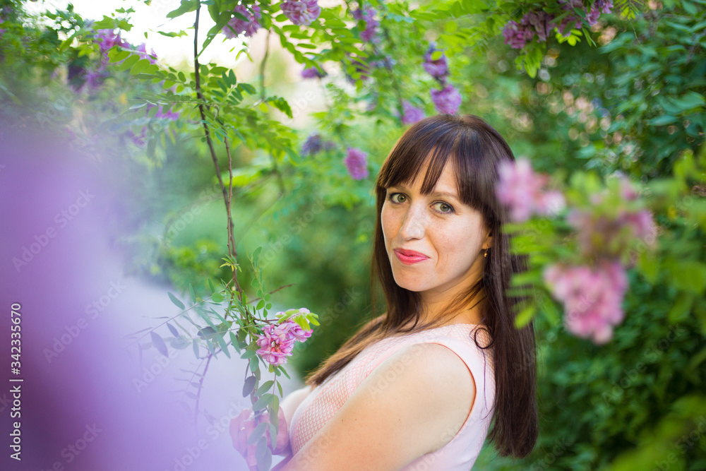 horizontal closeup portrait of a cute long-haired brunette in a pink dress on a background of nature horizontal closeup portrait of a cute long-haired brunette in a pink dress on a background of nature