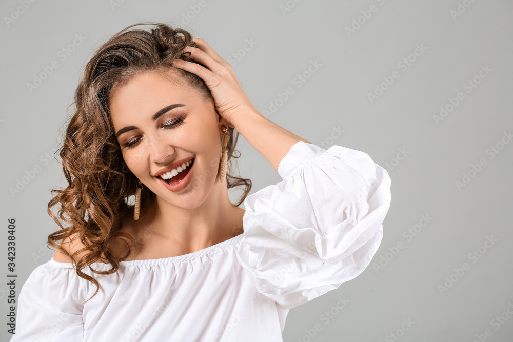 Beautiful young woman with curly hair on grey background Beautiful young woman with curly hair on grey background