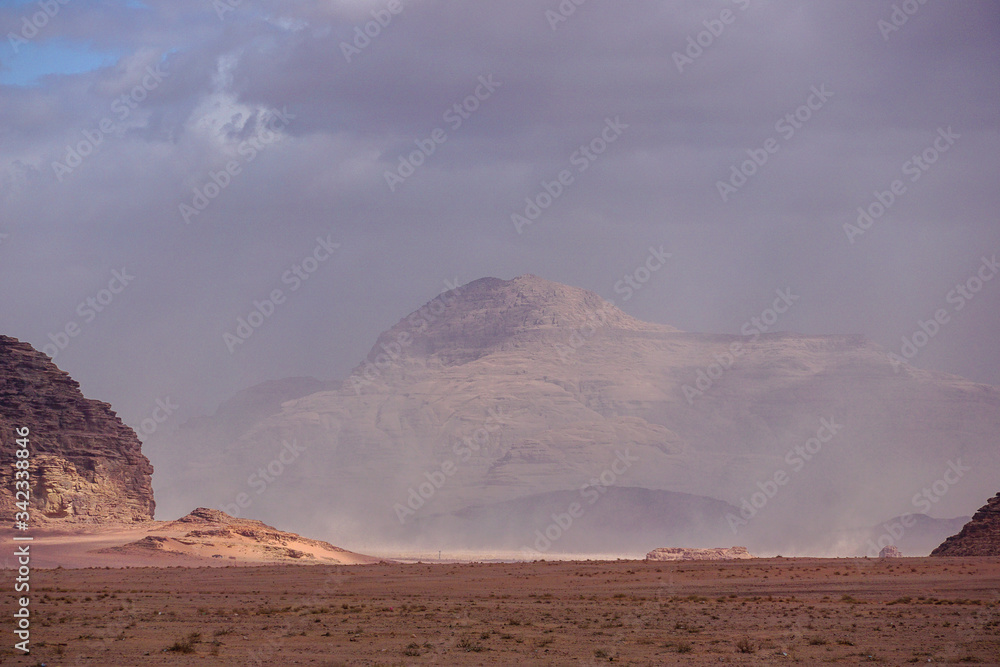 WADI RUM DESERT, JORDAN - FEBRUARY 08, 2020: Iluminated rock massifs emerging from a sand storm