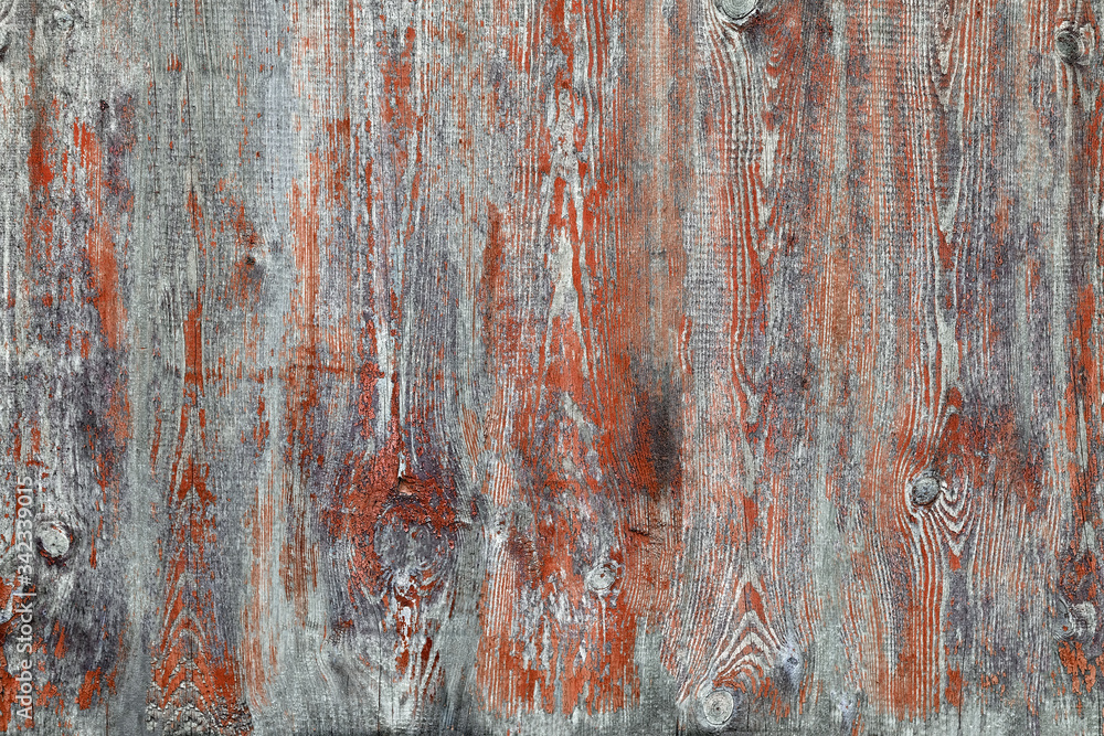 Old gray board faded red paint. Wood texture with peeling dry paint. Gray Wooden Background An old worn barn or antique wooden fence with chipped brown paint.