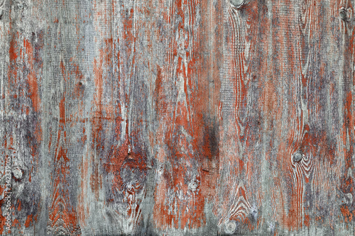 Old gray board faded red paint. Wood texture with peeling dry paint. Gray Wooden Background An old worn barn or antique wooden fence with chipped brown paint.