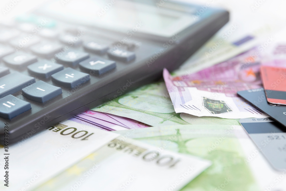 Scattered euro banknotes and a calculator. Crisis and unemployment during the coronavirus pandemic. Close-up. Flare. Scattered euro banknotes and a calculator. Crisis and unemployment during the coronavirus pandemic. Close-up. Flare.