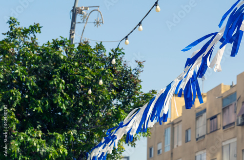 White and blue ribbons on sky background. Flags and decorations for the independence day (Yom Haatzmaut) in an Israeli city.