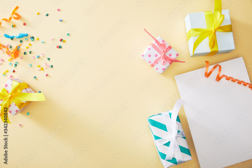 top view of festive colorful confetti and presents near blank paper on beige background top view of festive colorful confetti and presents near blank paper on beige background