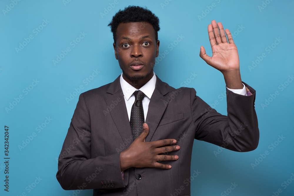 African american male in suit raising palm and holding hand on chest African american male in suit raising palm and holding hand on chest