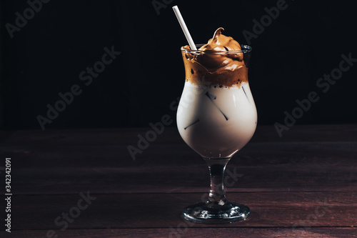 Cold trendy drink Korean dalgon iced coffee on a dark background. delicious and popular coffee in the trend photo