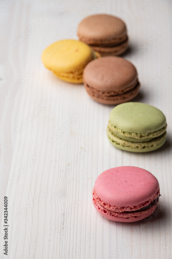Top view of colored macarons, with selective focus, on white wooden table, vertical, with copy space Top view of colored macarons, with selective focus, on white wooden table, vertical, with copy space