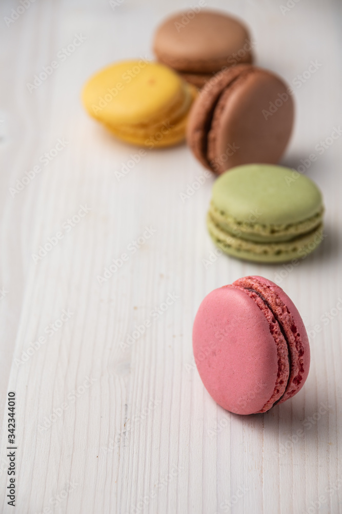 Close-up of colored macarons, with selective focus, on white wooden table, vertical, with copy space Close-up of colored macarons, with selective focus, on white wooden table, vertical, with copy space