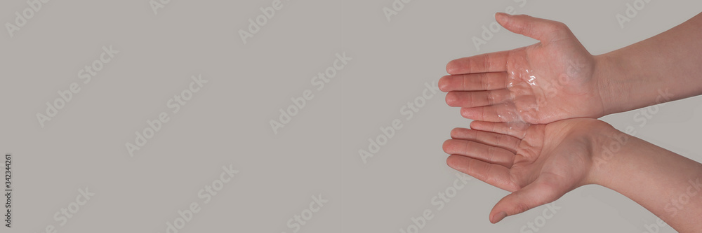 Fototapeta premium Hands of a young male with liquid soap in the palms on a grey background. Hand washing. Minimal hygiene, virus protection concept.