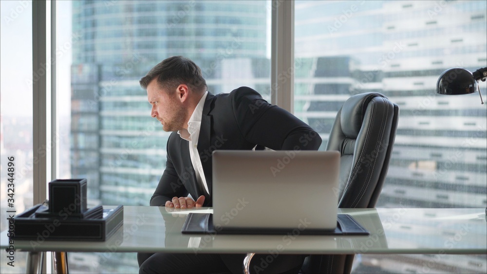 A businessman is sitting at a table in a luxurious office. A businessman in his office on a high floor in a skyscraper.