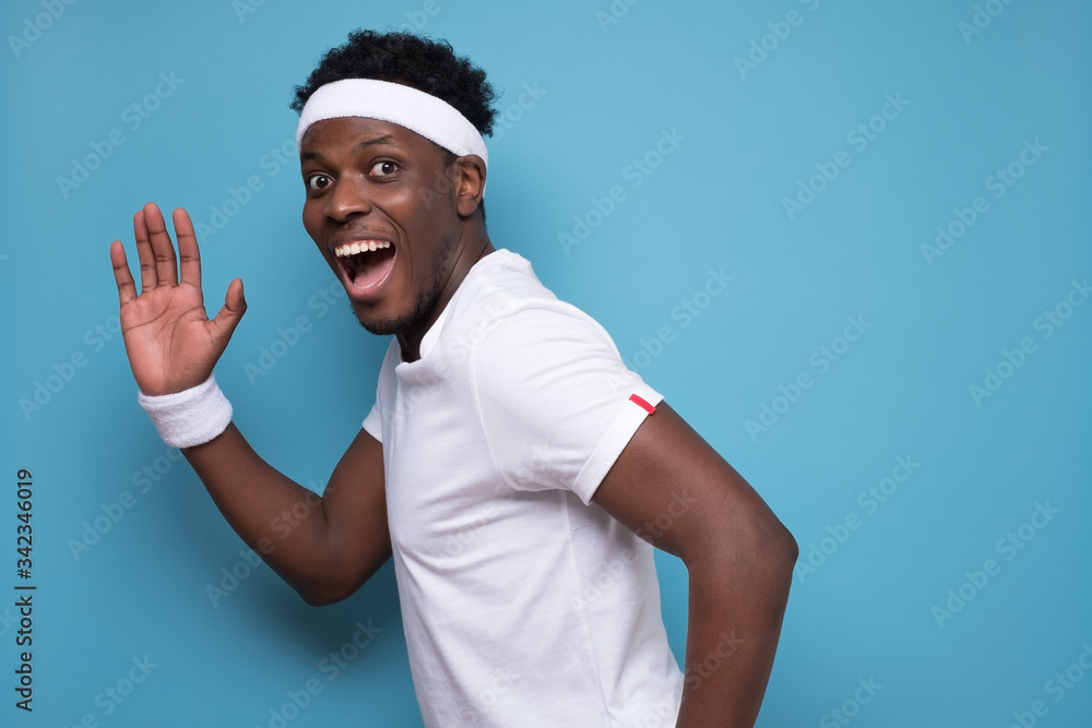 Fototapeta premium african american young man running away and looking at camera and waving hand