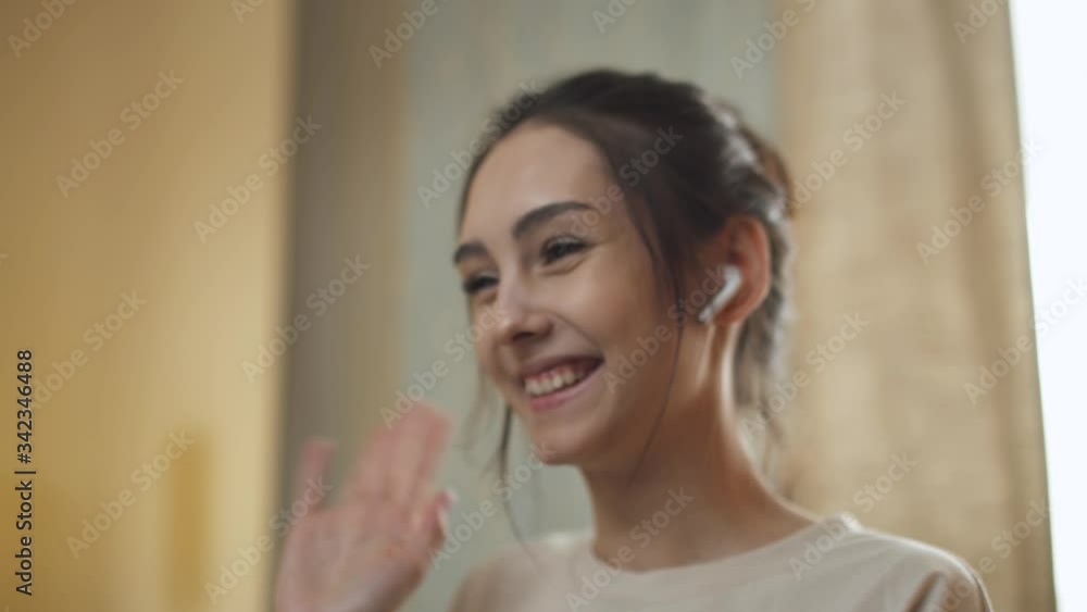 Young female in wireless headphones makes a video conference, working at a computer and communicates with the other person, remote work on quarantine. Young female in wireless headphones makes a video conference, working at a computer and communicates with the other person, remote work on quarantine.