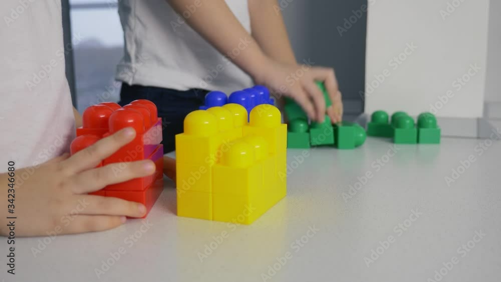 Happy children at home at the table build a house of colored cubes. Preschoolers play with Bricks. Happy children at home at the table build a house of colored cubes. Preschoolers play with Bricks.