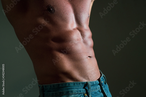 Masculine hard body. Fitness man showing six pack abs on grey background.