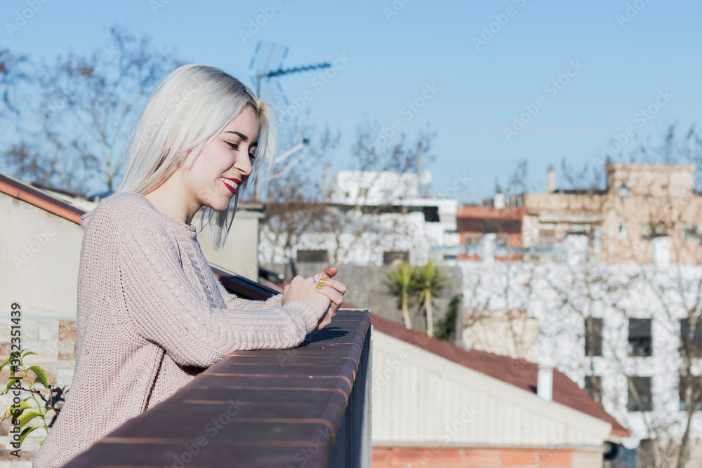 portrait of happy young woman on balcony looking away