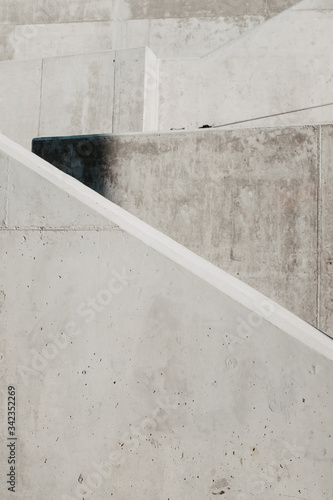 Escaleras con muros blancos de hormig  n y barandilla negra.