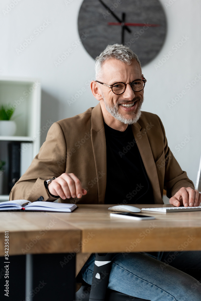 selective focus of cheerful businessman in glasses smiling in office selective focus of cheerful businessman in glasses smiling in office