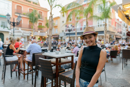 Happy young beautiful Asian tourist woman at the restaurant outdoors © Ranta Images