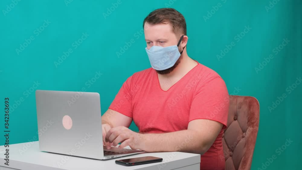 Man working from home. Using a smartphone. Bearded man in a protective mask works at home. Man working from home. Using a smartphone. Bearded man in a protective mask works at home.