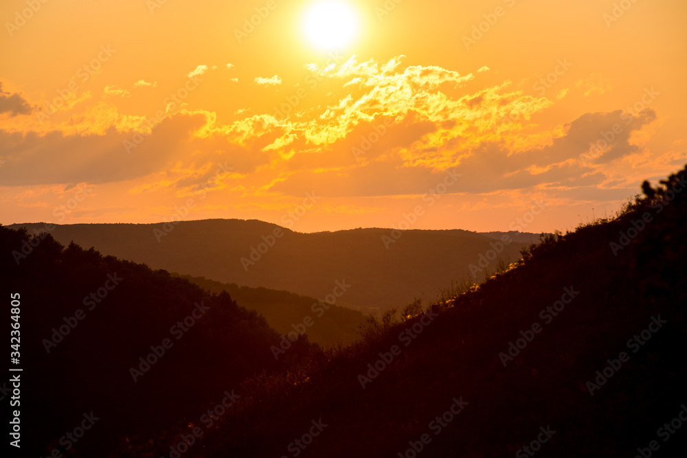 summer fiery red sunset in the mountains against the background of trees
