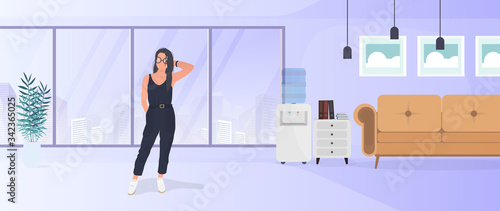 Brunette girl posing. Model in a stylish suit. Room, sofa, floor lamp, paintings on the wall, bookcase with books, a girl with black hair. Vector. © Javvani