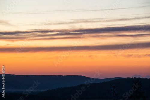 summer fiery red sunset in the mountains against the background of trees © Павел Чигирь