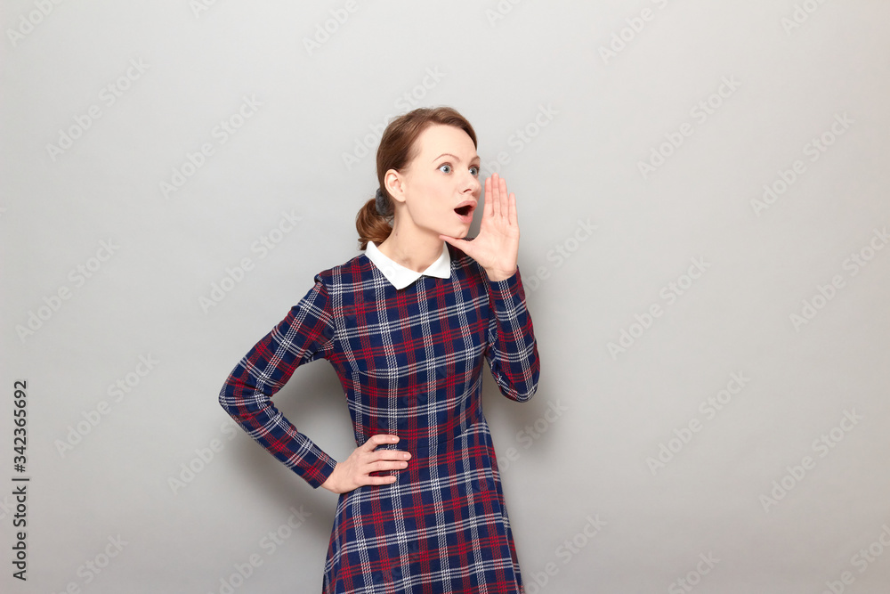 Portrait of amazed girl screaming loudly to side with hand near mouth Portrait of amazed girl screaming loudly to side with hand near mouth