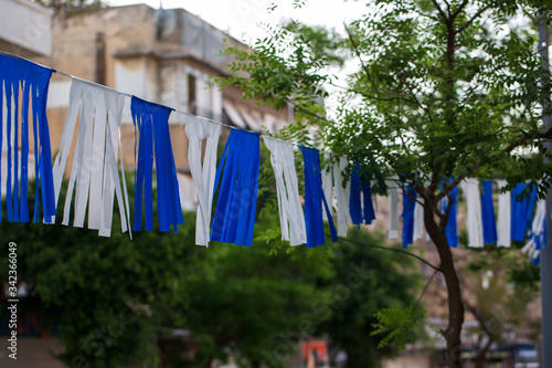 White and blue ribbons on sky background. Flags and decorations for the independence day (Yom Haatzmaut) in an Israeli city.