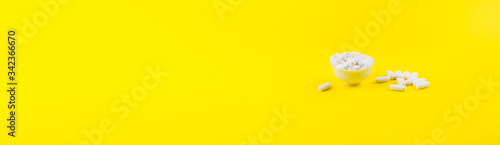 White magnesium citrate supplement pills on color yellow background. Generic pills concept web banner photo