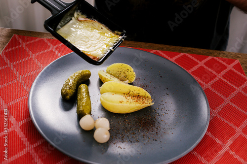 Swiss traditional dish called raclette including steamy potatoes, melted cheese and pickles eaten at christmas and wintertime