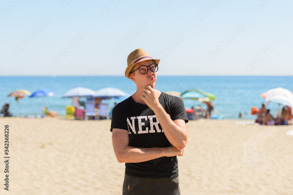 Young nerd tourist man thinking at the beach