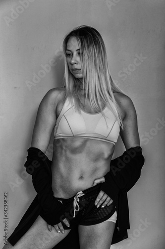 Sports muscular woman portrait wearing black sportswear over grey. Attractive sexy caucasian woman with long blond hair in studio shot.