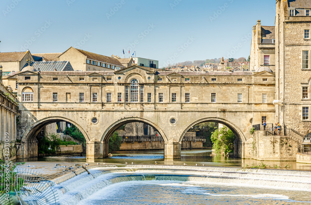 Pulteney Bridge over the River Avon with the weir in the city of Bath, Somerset, UK on a clear and sunny Spring morning