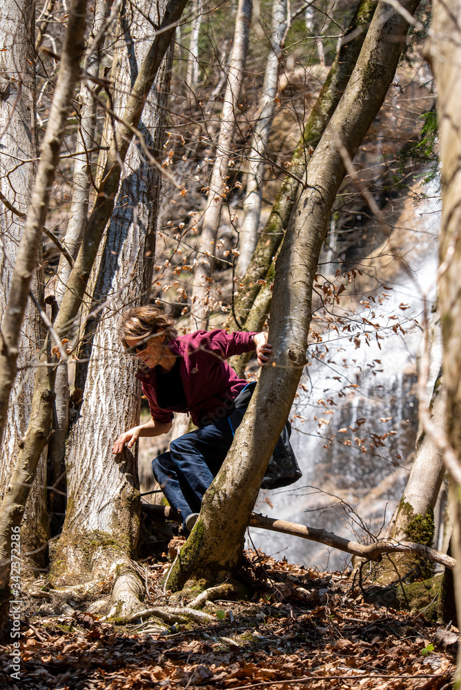 Woman hiking in the woods with a waterfall in the background