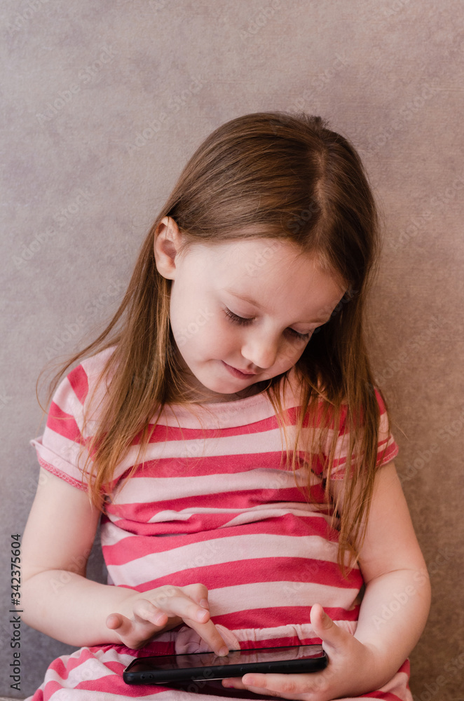 little girl enthusiastically controls the phone. online learning games mobile, ecaucasian, internet, cute little girl enthusiastically controls the phone. online learning games mobile, ecaucasian, internet, cute