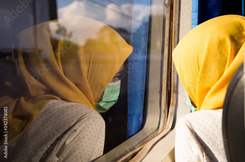 Reflection of a young woman with a mask looking out of the train's window photo