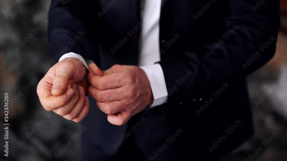The groom buttons up the cuffs close-up. The groom buttons up the cuffs close-up.