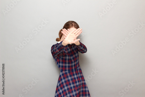 Portrait of girl stretching palms to camera and covering her face