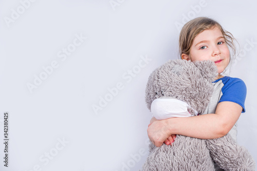 Coronavirus protection concept, girl child in a mask with a plush toy bear. COVID-19 Virus protection, social distance, white background copy space photo