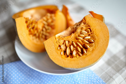 Pumpkin slices on a white plate on a table with blue napkin. Fresh pieces of pumpkin with seeds